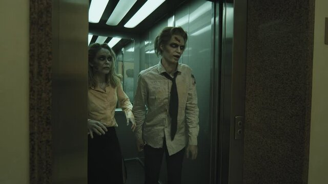 Slowmo shot of zombie man and woman in SFX makeup and dirty clothes walking out of elevator