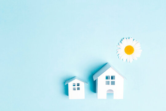 Small toy houses with sun chamomile on a blue background. Summer vacation concept.