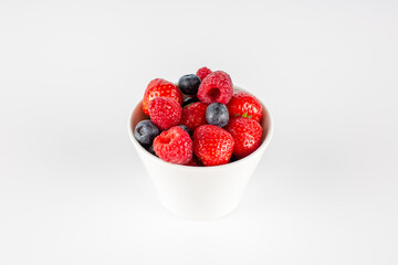 strawberries, raspberries, blueberries in a white bowl on a white background