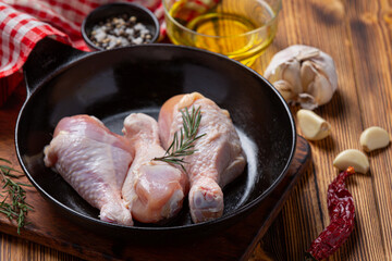 Raw uncooked chicken legs on the dark wooden background.