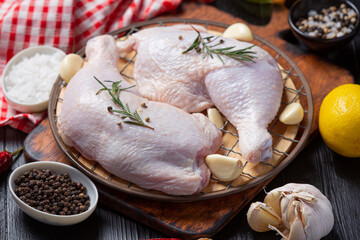 Raw chicken thighs on the dark wooden background.