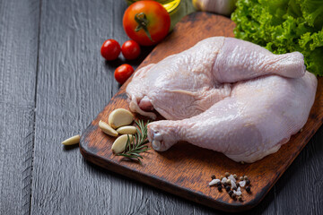 Raw chicken thighs on the dark wooden background.