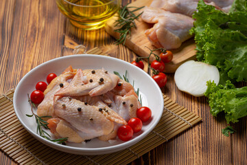 Raw chicken wings on the dark wooden background.