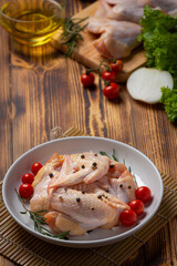 Raw chicken wings on the dark wooden background.