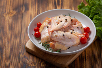 Raw chicken wings on the dark wooden background.