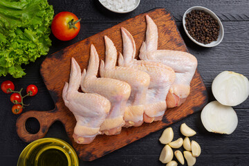 Raw chicken wings on the dark wooden background.