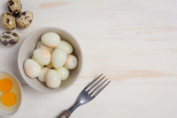 boiled quail eggs on the white wooden background.