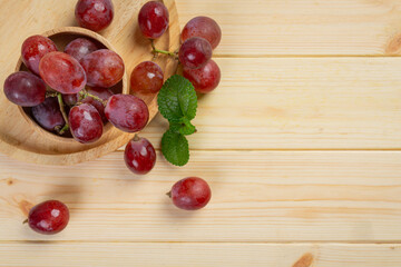 Bunches of fresh ripe red grapes on the wooden background.