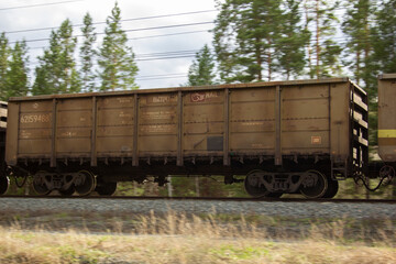 Fototapeta na wymiar A gondola car as part of a train. A gondola car as part of a freight train rushes along the rails.