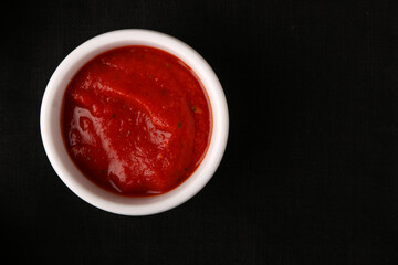 ketchup tomatoes sauces in bowl on black
