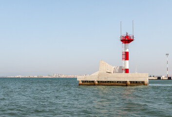 A small lighthouse is located on the breakwater at the exit from the water area in the Mediterranean port of Haifa in Israel