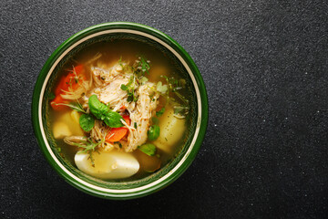 Chicken noodle soup with egg, vegetables and chicken meat on dark backdrop top view