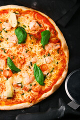 seafood pizza with shrimp and tomatoes on dark background top and pizza knife