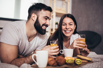 Cute couple having breakfast and drink coffee in the bedroom.