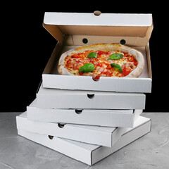 stack of pizza box with pizza inside. pizza delivery. box on black background. meat pizza