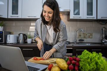 woman cooking checking recipe at laptop