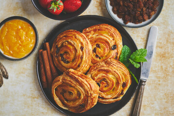 Delicious, fresh baked cinnamon buns served on black ceramic plate. With various sides