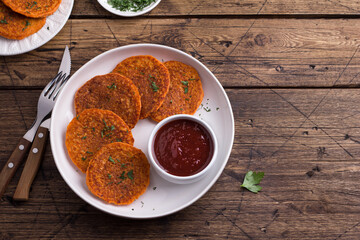 Lentil fritters with plum sauce, tkemali, greens in white plate on wooden table. Healthy vegan food	