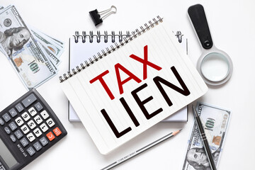 Tax Lien. notebook on white workspace. near the notepad dollar bills and a calculator