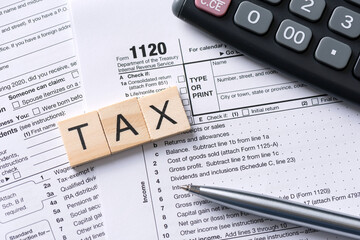 Tax word made of wooden tiles. US tax form on desk