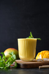 Indian ayurvedic mango lassie or lassi on black background. Vertical format. Traditional healthy...