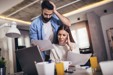 Fototapeta premium Cheerful loving young couple using laptop and analyzing their finances