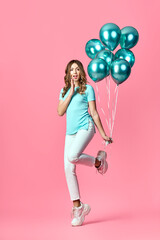 Full length portrait of happy surprised woman with blue balloons in hands on pink background.