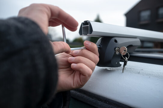 Hands with a screwdriver installs attachments for the trunk or cargo box on the roof of the car.