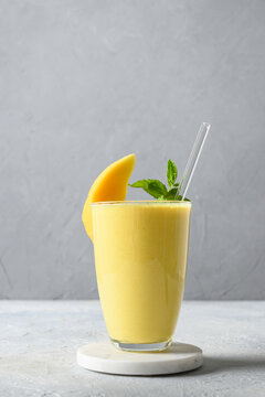 Indian ayurvedic mango lassie or lassi on light gray background. Vertical format. Traditional healthy drink with mango. Freshness lassi made of yogurt, water, spices, fruits and ice.