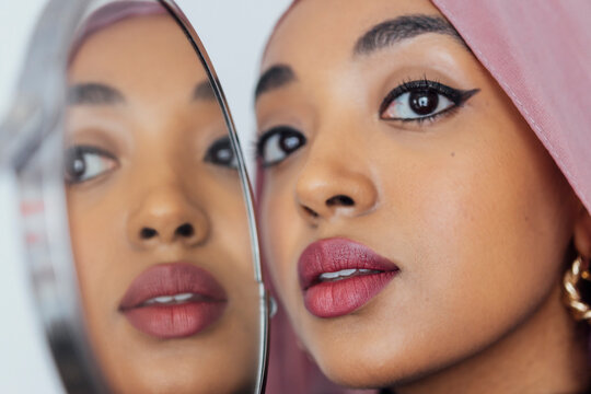Reflection of a Black Muslim woman in a pink hijab