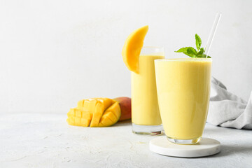 Two mango lassi in glasses on gray background with copy space. Indian healthy ayurvedic cold drink...