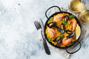 Foto op Canvas Traditional spanish seafood paella in pan with chickpeas, shrimps, mussels, squid on light grey concrete background. Top view with copy space © Vasiliy