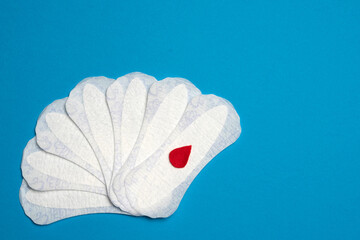 Sanitary pads and a red drop, isolated on blue background.