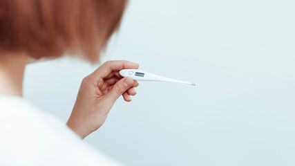 Woman looking at temperature on an electronic thermometer