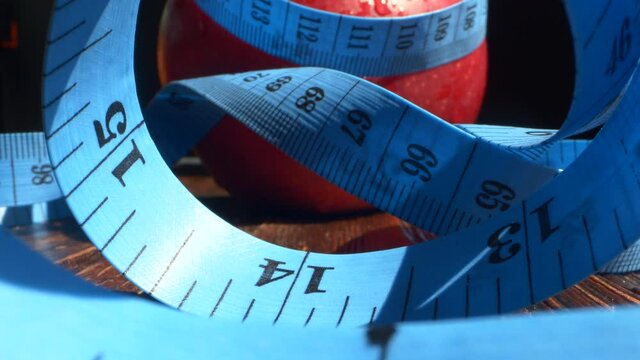 Red apple wrapped with measuring tape. Diet, healthy eating, weight loss concept