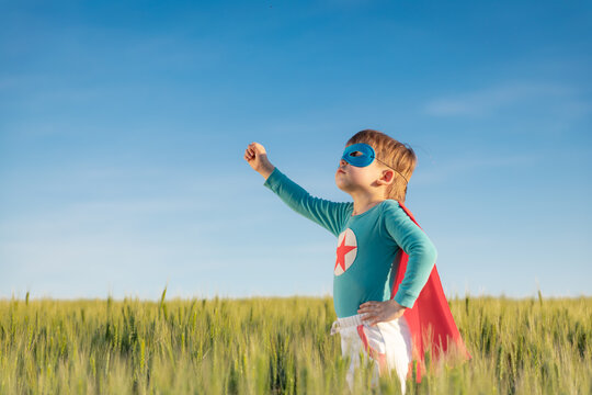 Superhero child playing outdoor in green field
