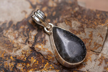 Silver metal mineral stone pendant on rocky background - 434320611