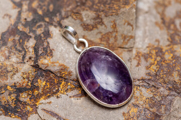 Silver metal mineral stone pendant on rocky background