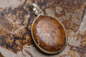 Silver metal mineral stone pendant on rocky background
