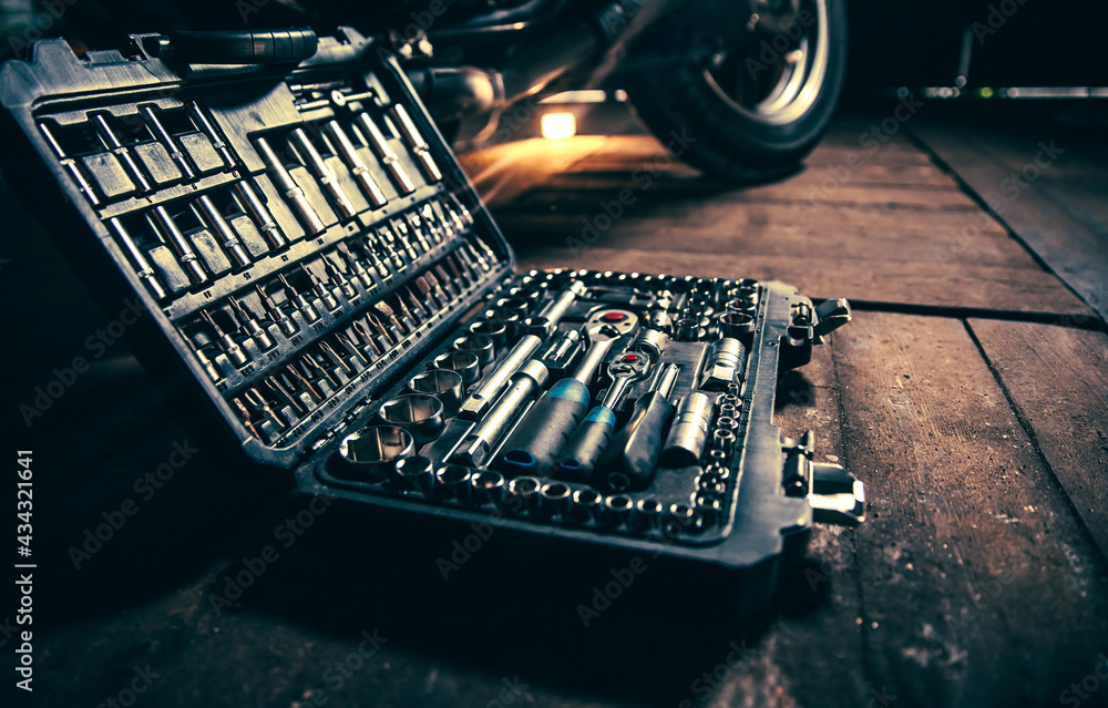 Wall mural Tool box on a wooden floor against the background of a motorcycle wheel