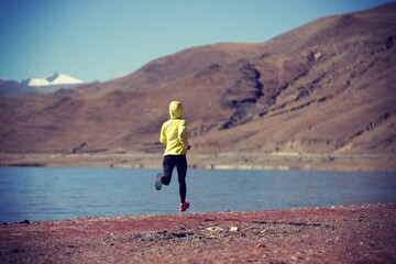 Woman trail runner cross country running  in winter lakeside