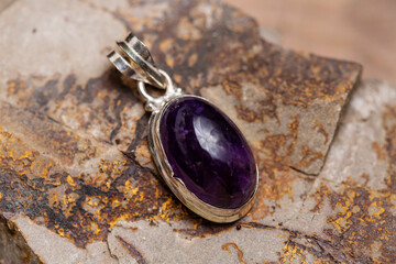 Silver metal mineral stone pendant on rocky background