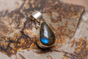 Silver metal mineral stone pendant on rocky background