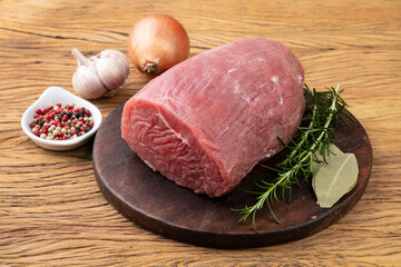 Raw eye round meat over wooden board with seasonings