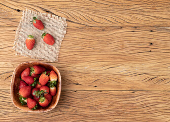 Strawberries in a bowl over wooden table with copy space