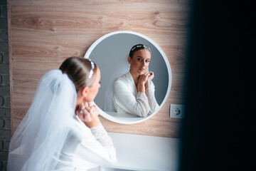 Woman in wedding robe and veil sitting at dressing table