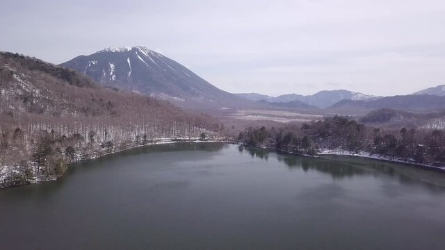 Aerial View of Large Lake with Snowy Forest and Mountain Range Japan 4K
