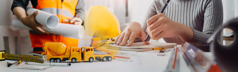 engineer working at a drawings of house in office for discussing. Engineering tools and construction concept.