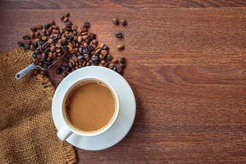 cup of coffee and coffee beans in a sack on  Brown background, top view