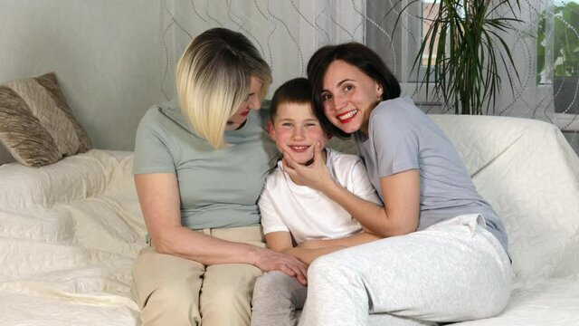Happy smiling family, mother son and grandmother sitting on sofa in modern scandinavian apartment. White teeth. Family concept.
